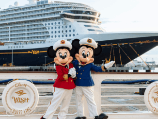 Captain Mickey and Captain Minnie standing in front of the Disney Wish