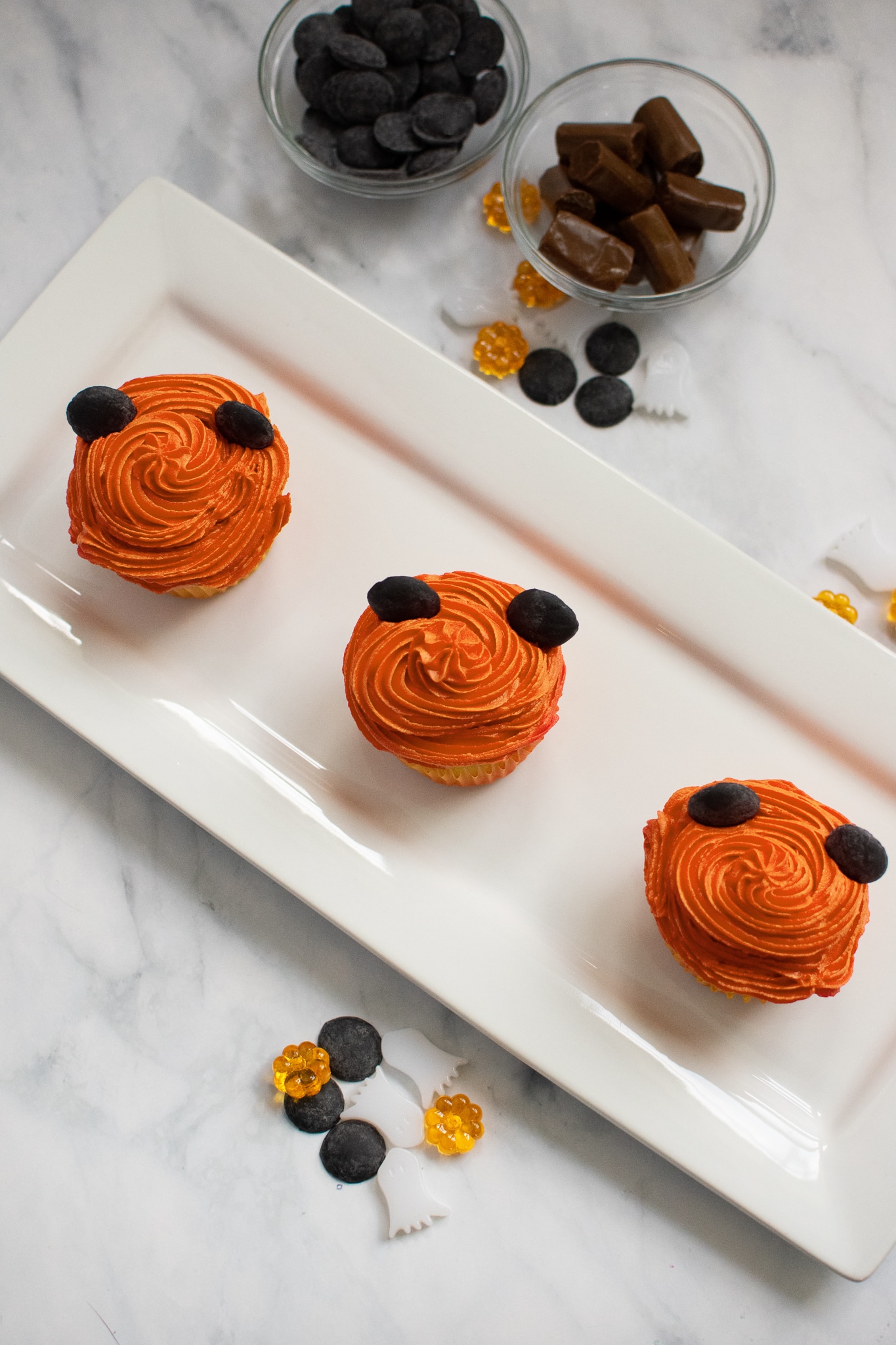 Decorating Mickey Pumpkin Cupcakes with Orange icing.