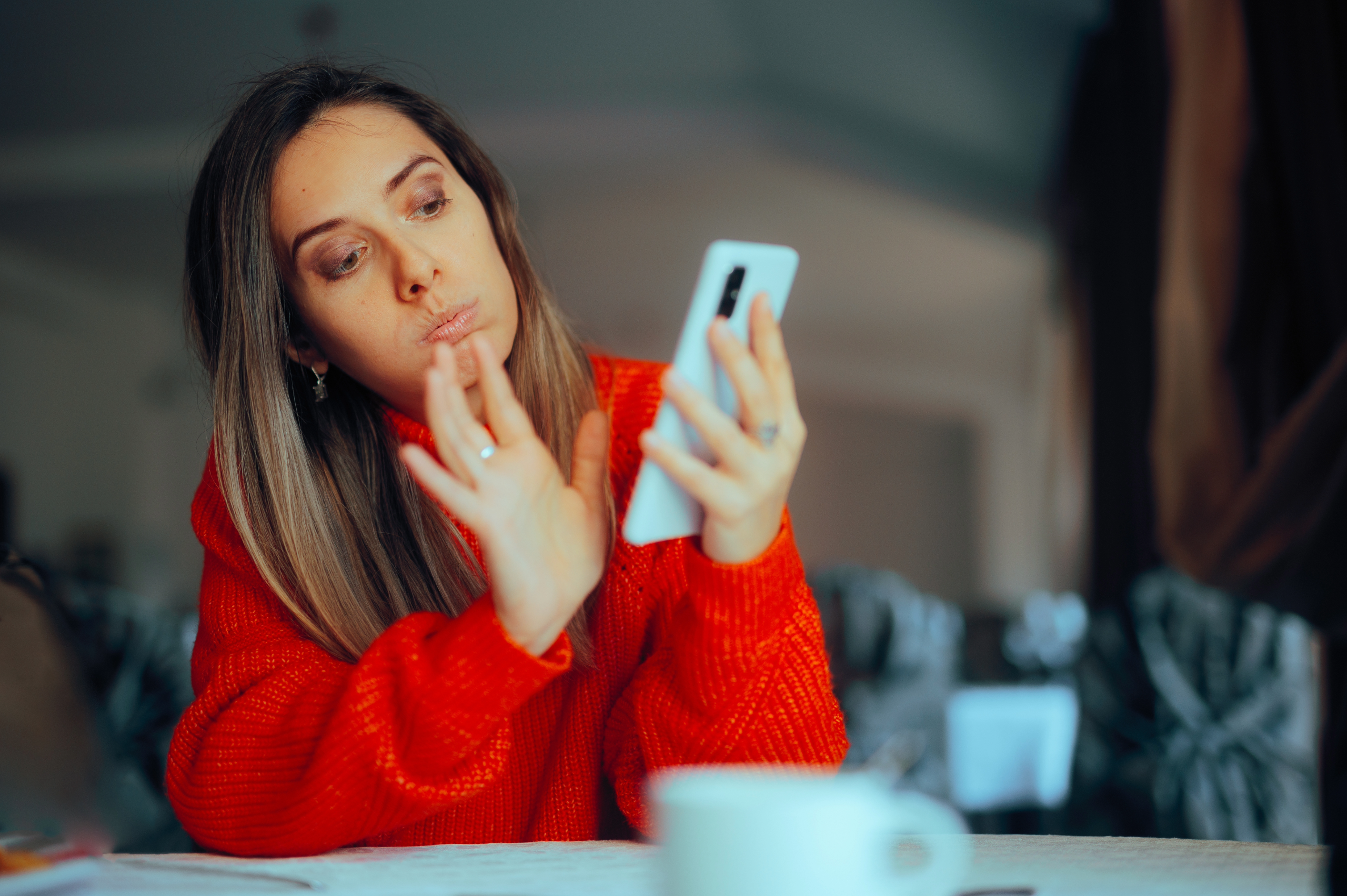 Woman swiping right on her phone while drinking coffee 