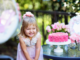 Little girl in pink excited about her birthday party in New Orleans in a park with pink cake and decorations