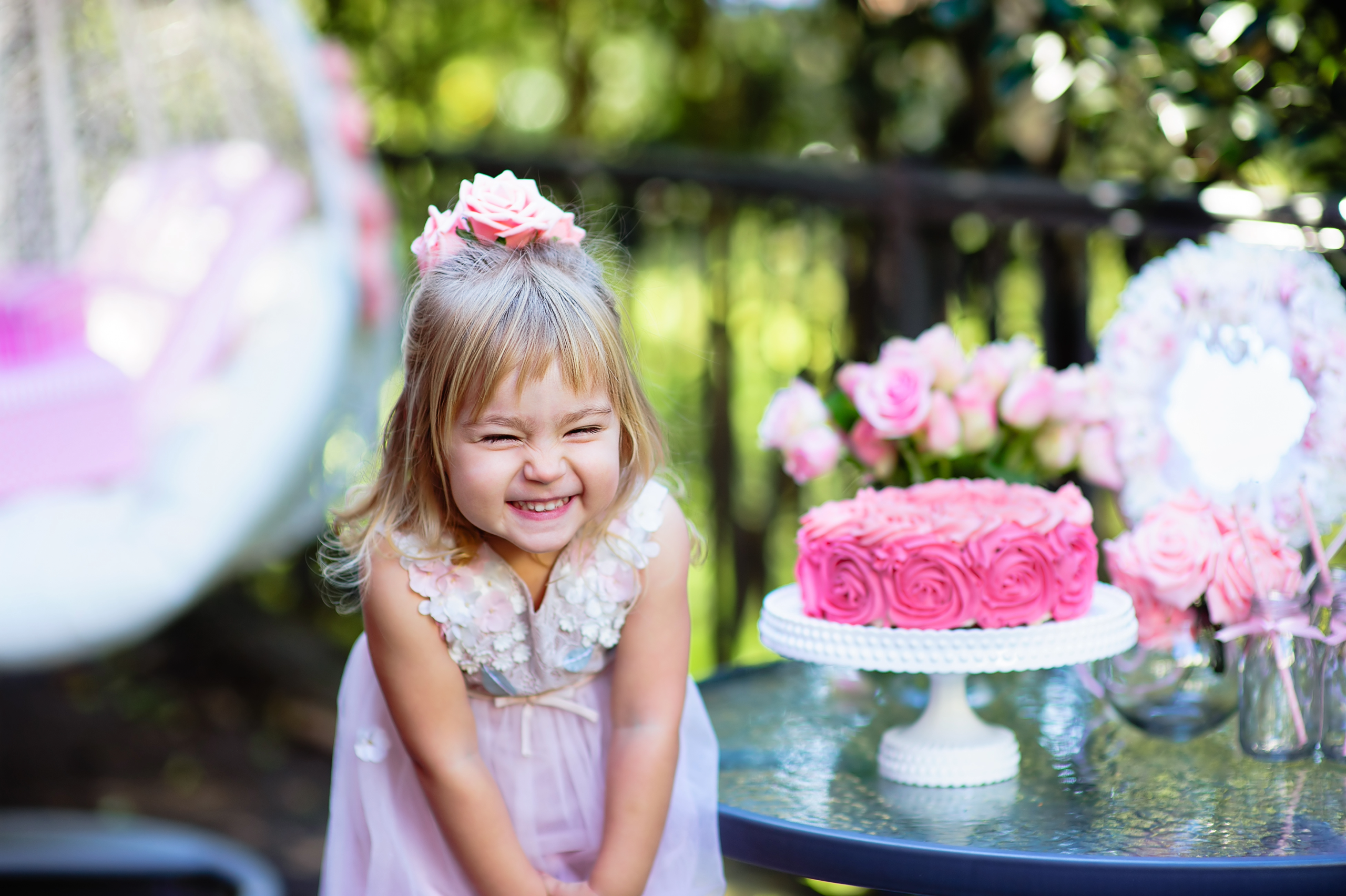 Little girl in pink excited about her birthday party in New Orleans in a park with pink cake and decorations